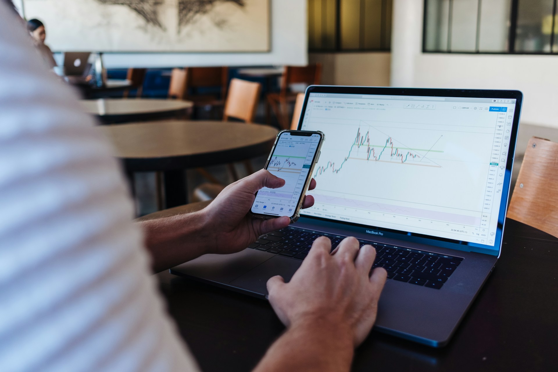 man checking his phone and computers for stock information